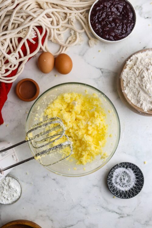 Creamy butter and sugar mixture ready for baking, surrounded by flour, eggs, and baking ingredients.