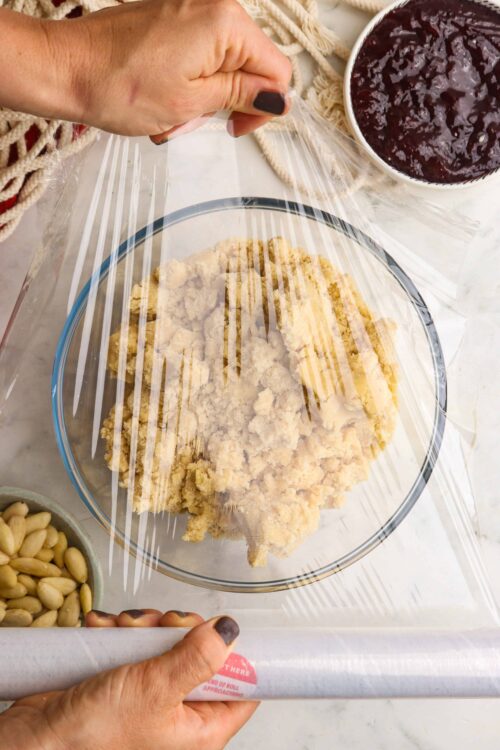 Flour mixture being covered with plastic wrap for baking process.