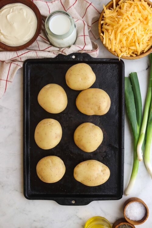 Fresh potatoes on a baking sheet for creamy scalloped potatoes recipe.