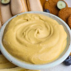 Butter spread with bananas, blueberry cookies, and sandwich cookies on a serving platter.