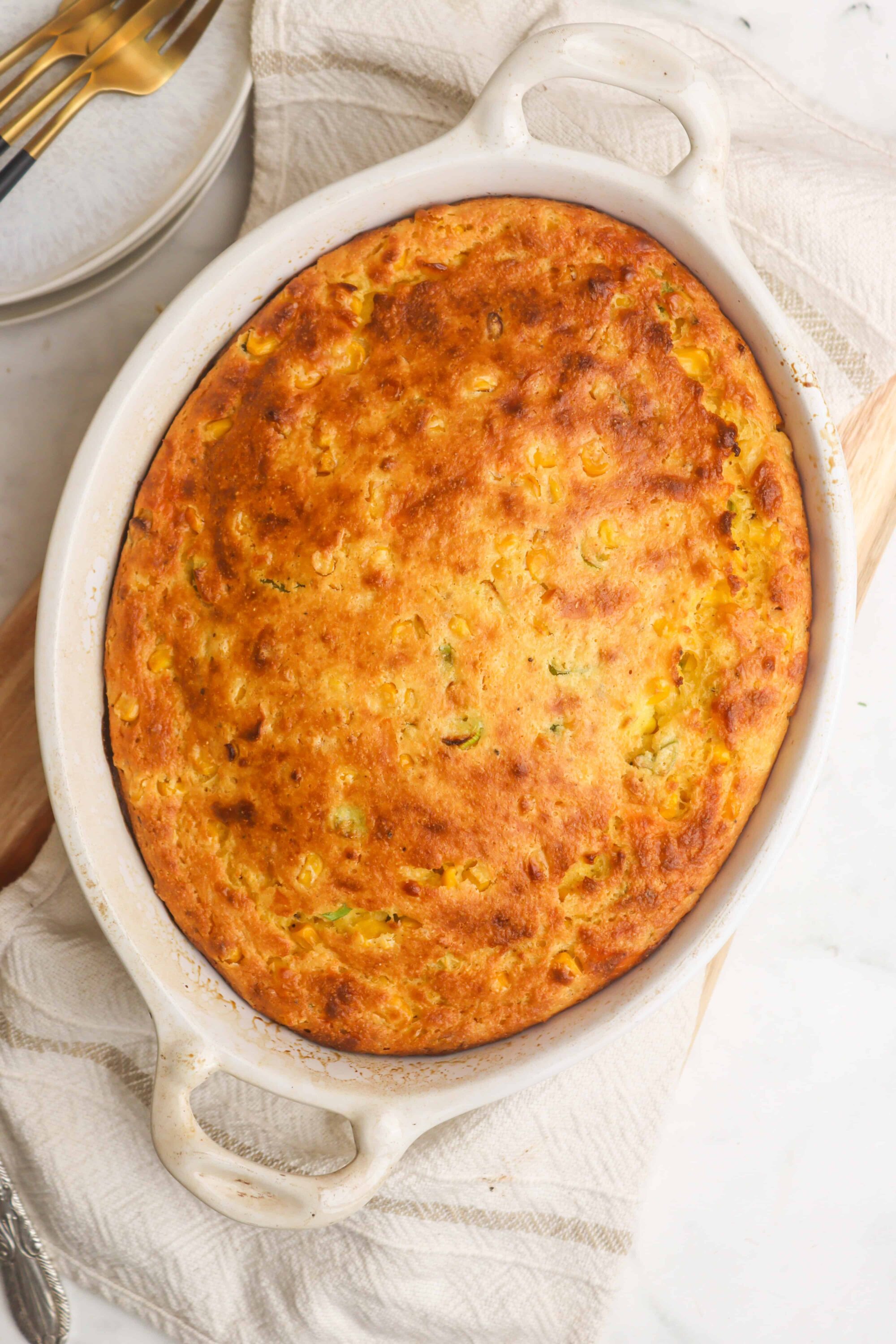 Golden baked casserole with corn and vegetables in a white baking dish.