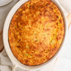 Golden baked casserole with corn and vegetables in a white baking dish.