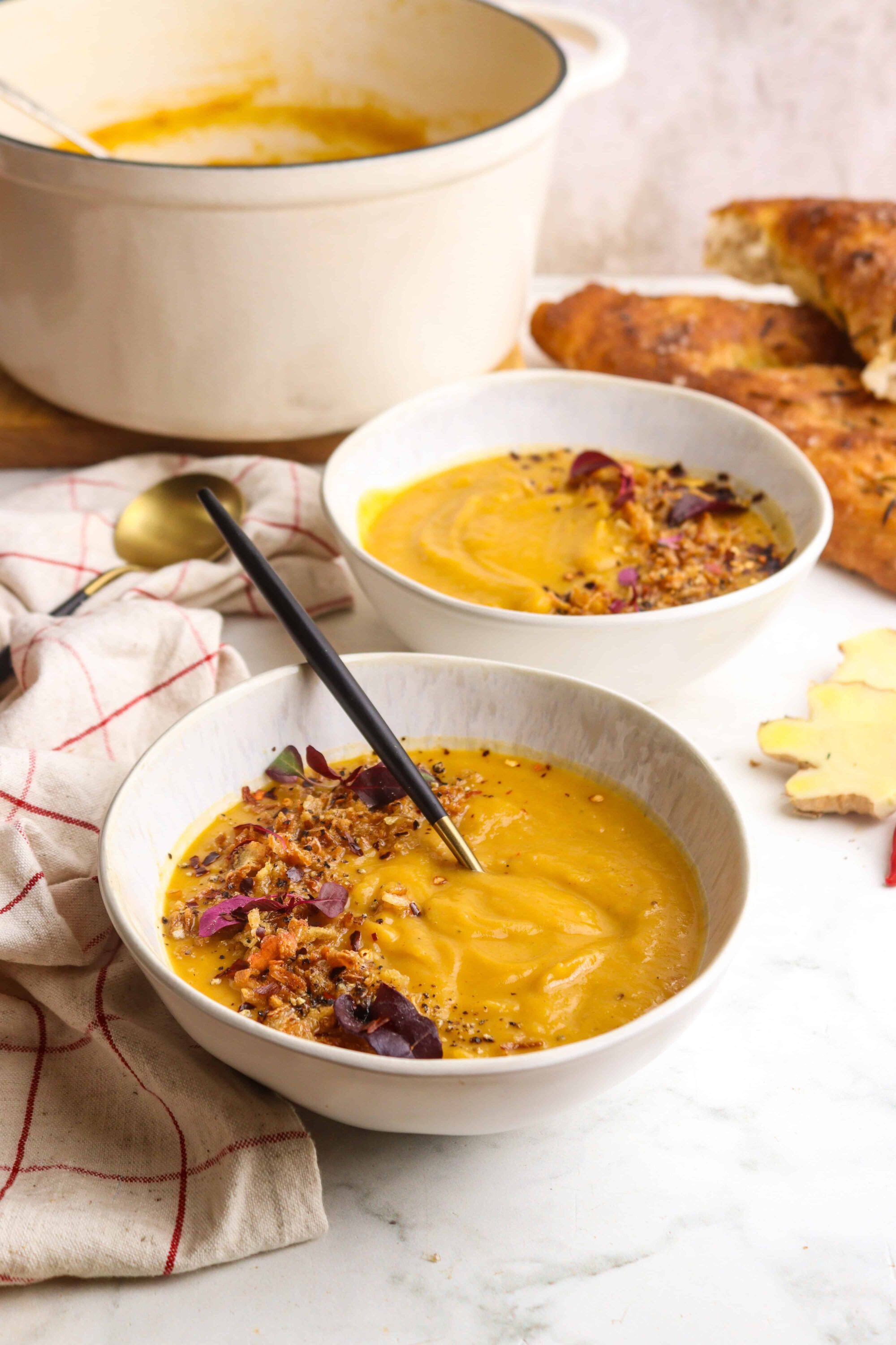 Silky butternut squash soup garnished with toasted seeds and herbs, served in white bowls for cozy fall meals.