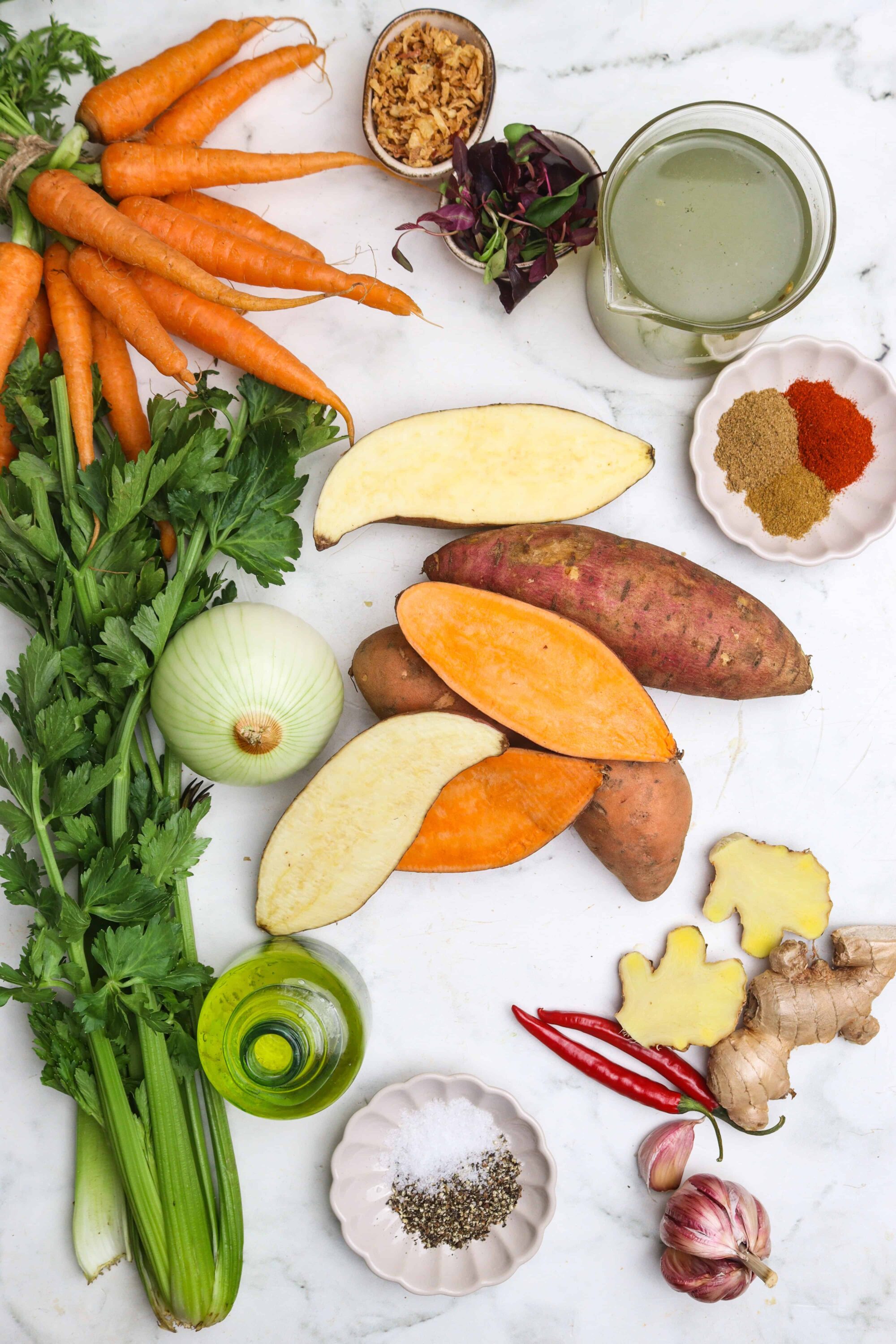 Fresh carrots, sweet potatoes, and aromatics for healthy cooking. Perfect ingredients for delicious, flavorful recipes.