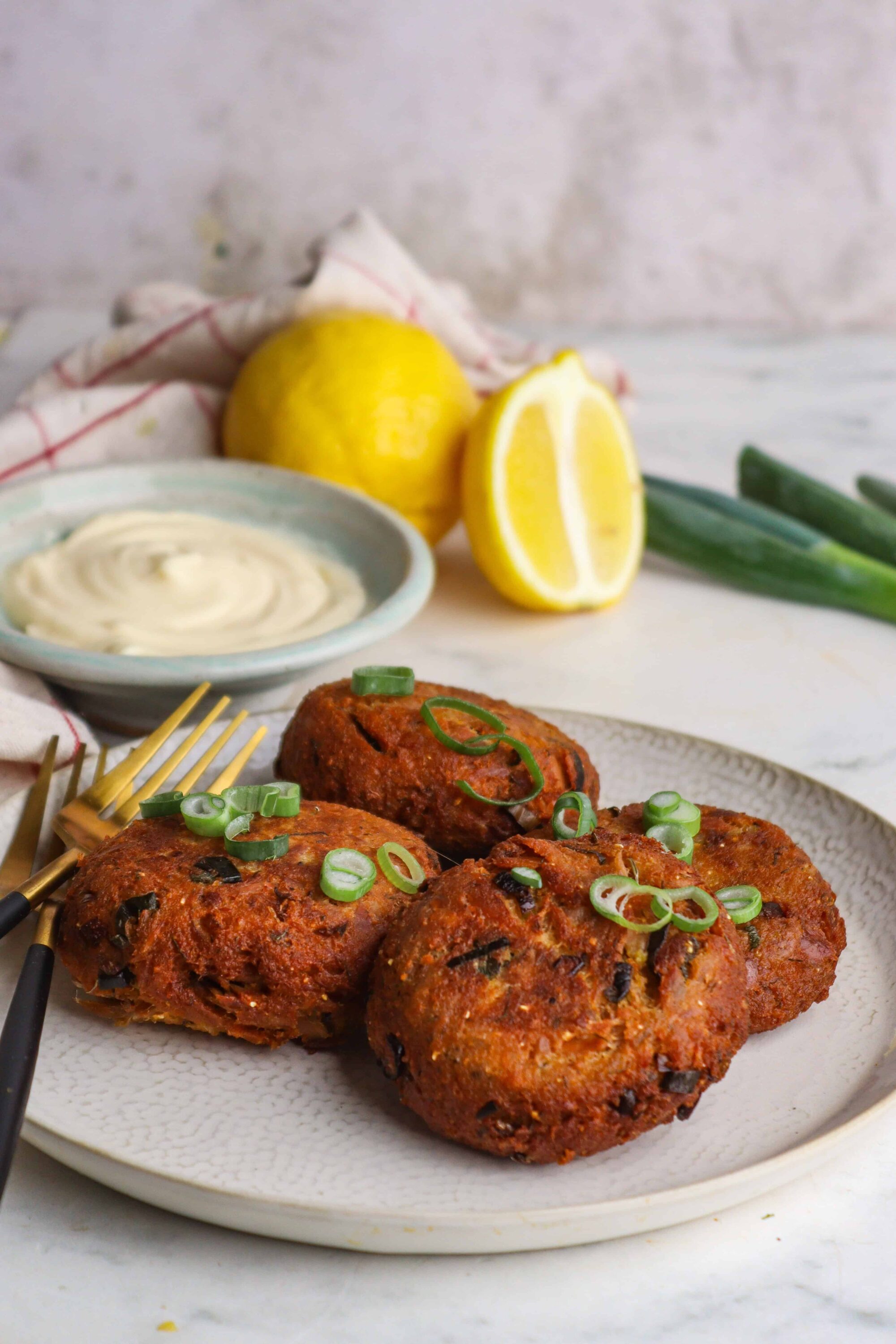 Crispy vegetarian chickpea cakes with green onions on a white plate.