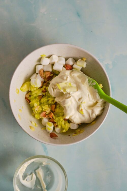 Cream cheese and pistachio fluff bowl with mini marshmallows and chopped nuts for a tasty treat.