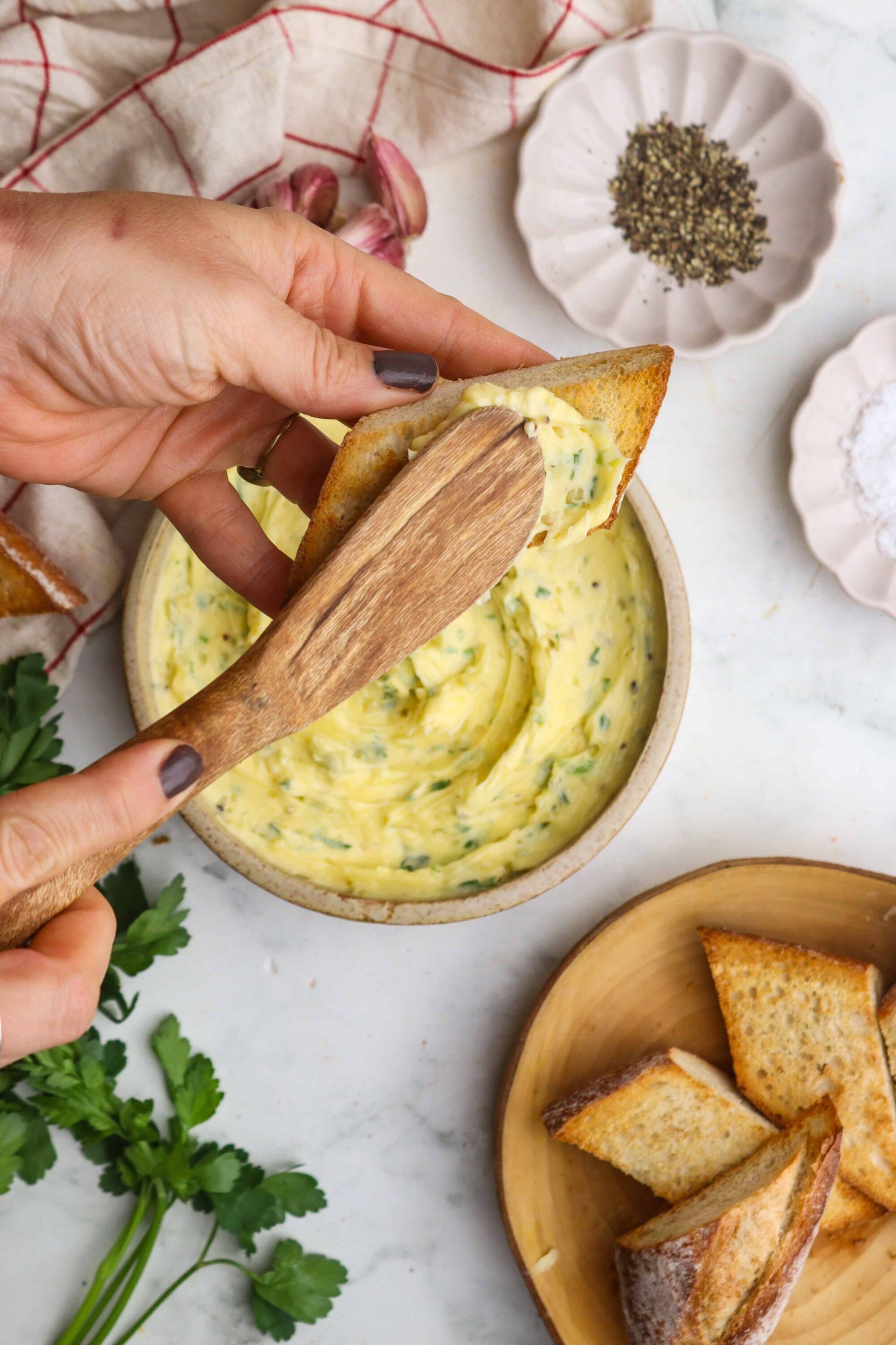 Creamy herb butter being spread on toasted bread for a delicious snack or appetizer.