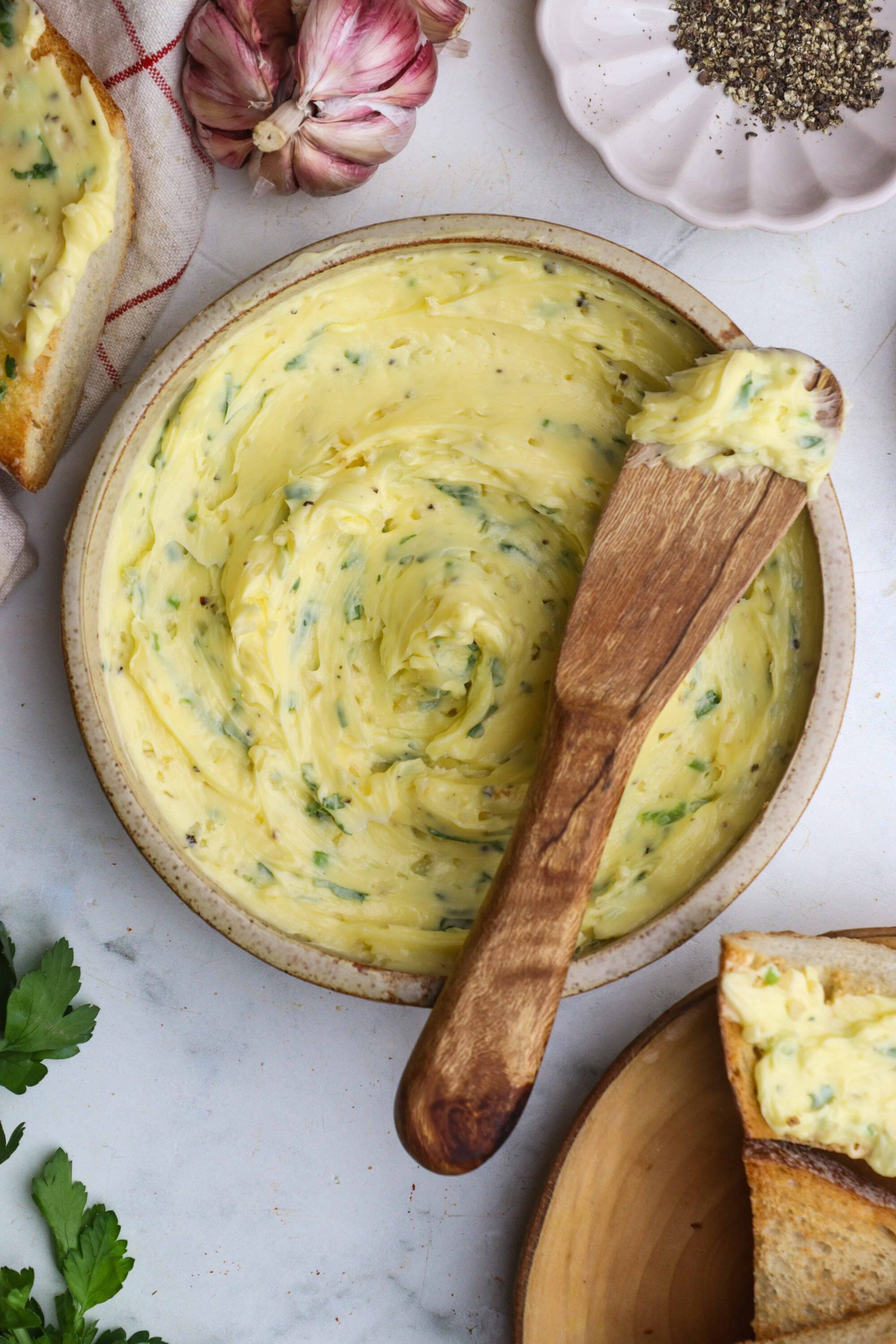 Creamy herbed garlic butter spread in a rustic bowl, perfect for bread and toasted dishes. Fresh garlic and herbs boost flavor.