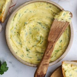 Creamy herbed garlic butter spread in a rustic bowl, perfect for bread and toasted dishes. Fresh garlic and herbs boost flavor.
