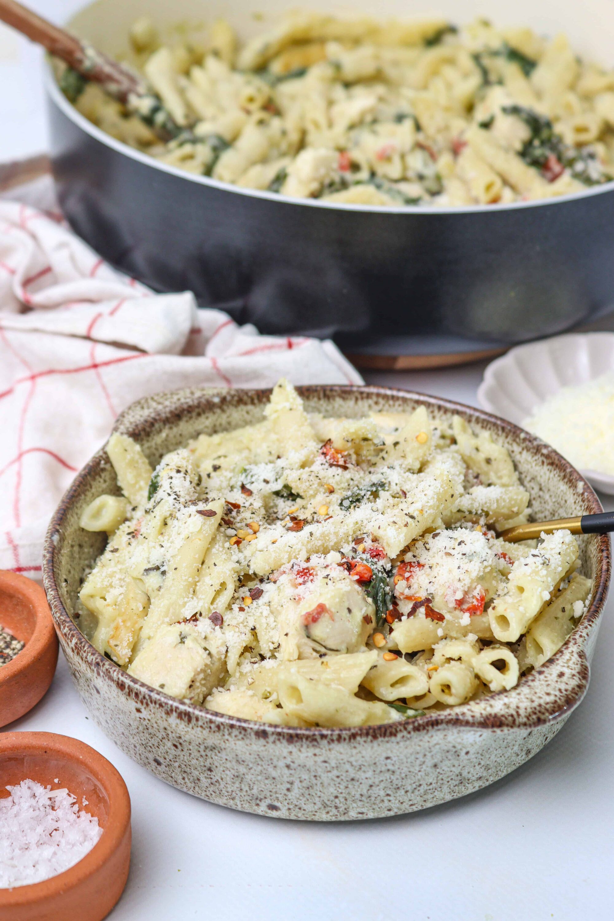 Creamy pasta with cheese, spinach, and cherry tomatoes in a rustic bowl.