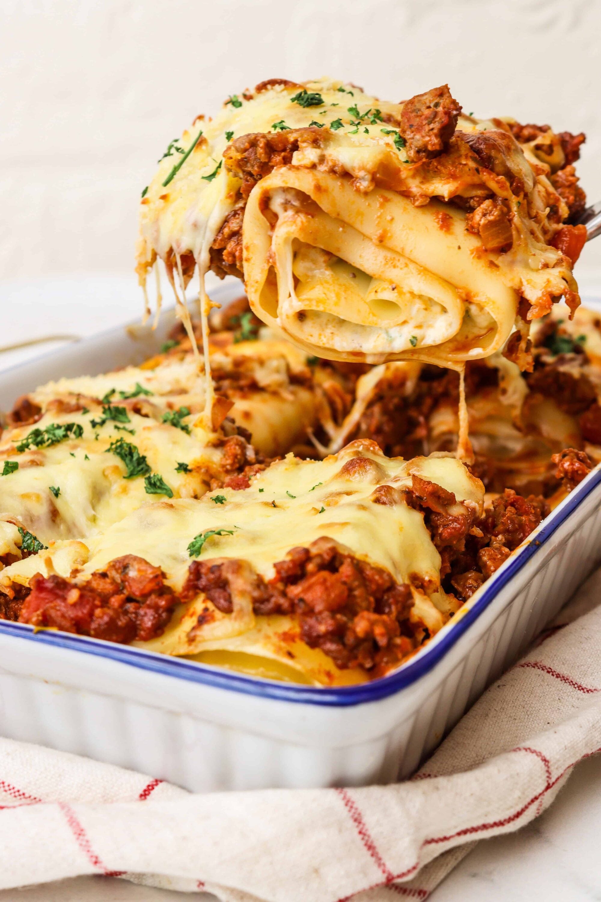 Savory baked lasagna with meat sauce, melted cheese, and herbs in a white baking dish.
