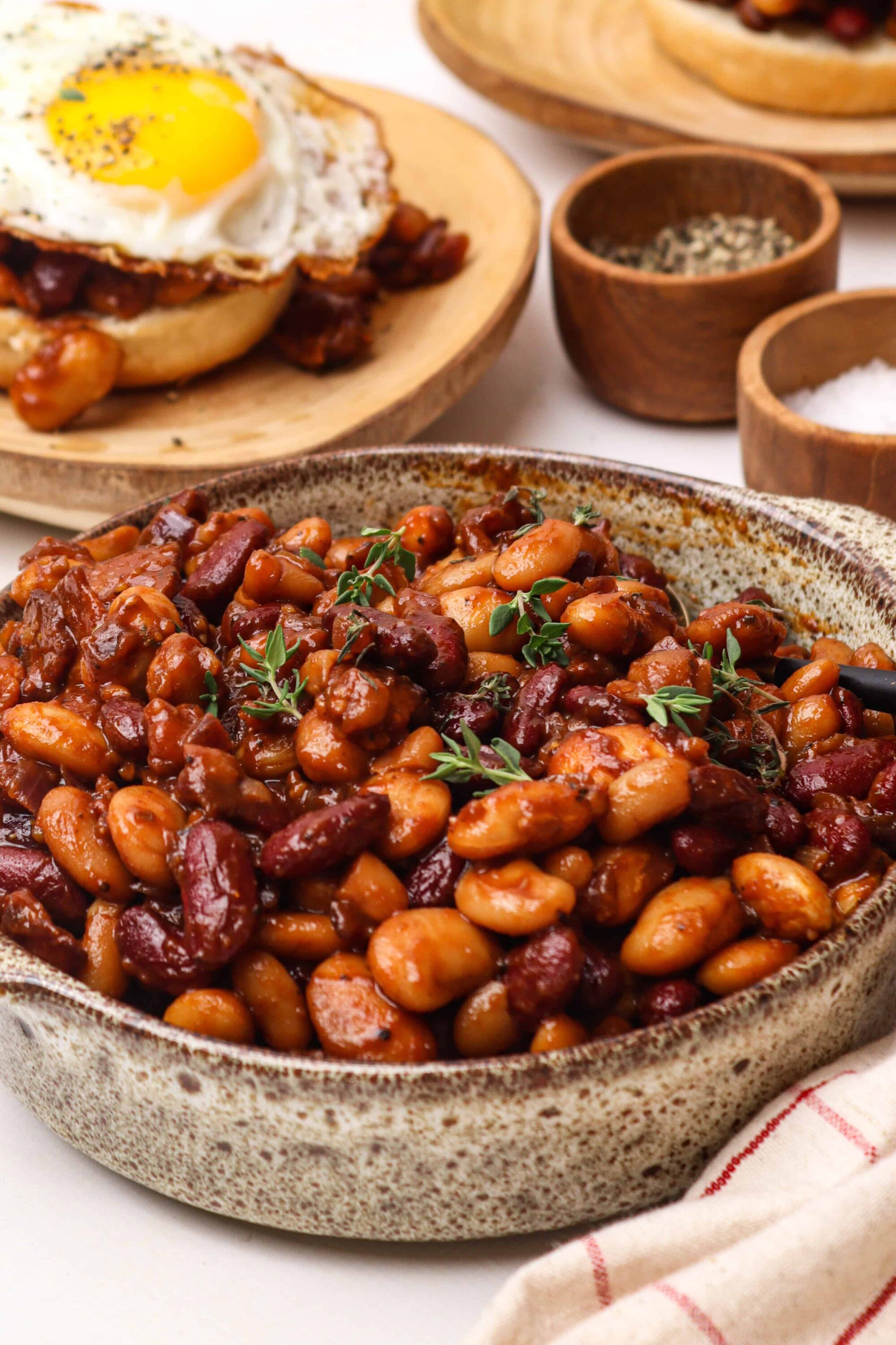 Savory baked beans with herbs in a rustic bowl for hearty comfort food.
