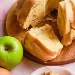 Butter cake with almonds on wooden board, sliced and served with fresh green apple and eggs, cozy dessert idea, baked Bree, homemade baked goods, sweet treat, classic cake.