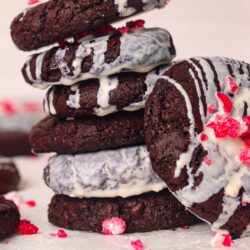 Fudgy chocolate cookies drizzled with white chocolate and topped with red sprinkles, perfect for dessert lovers.