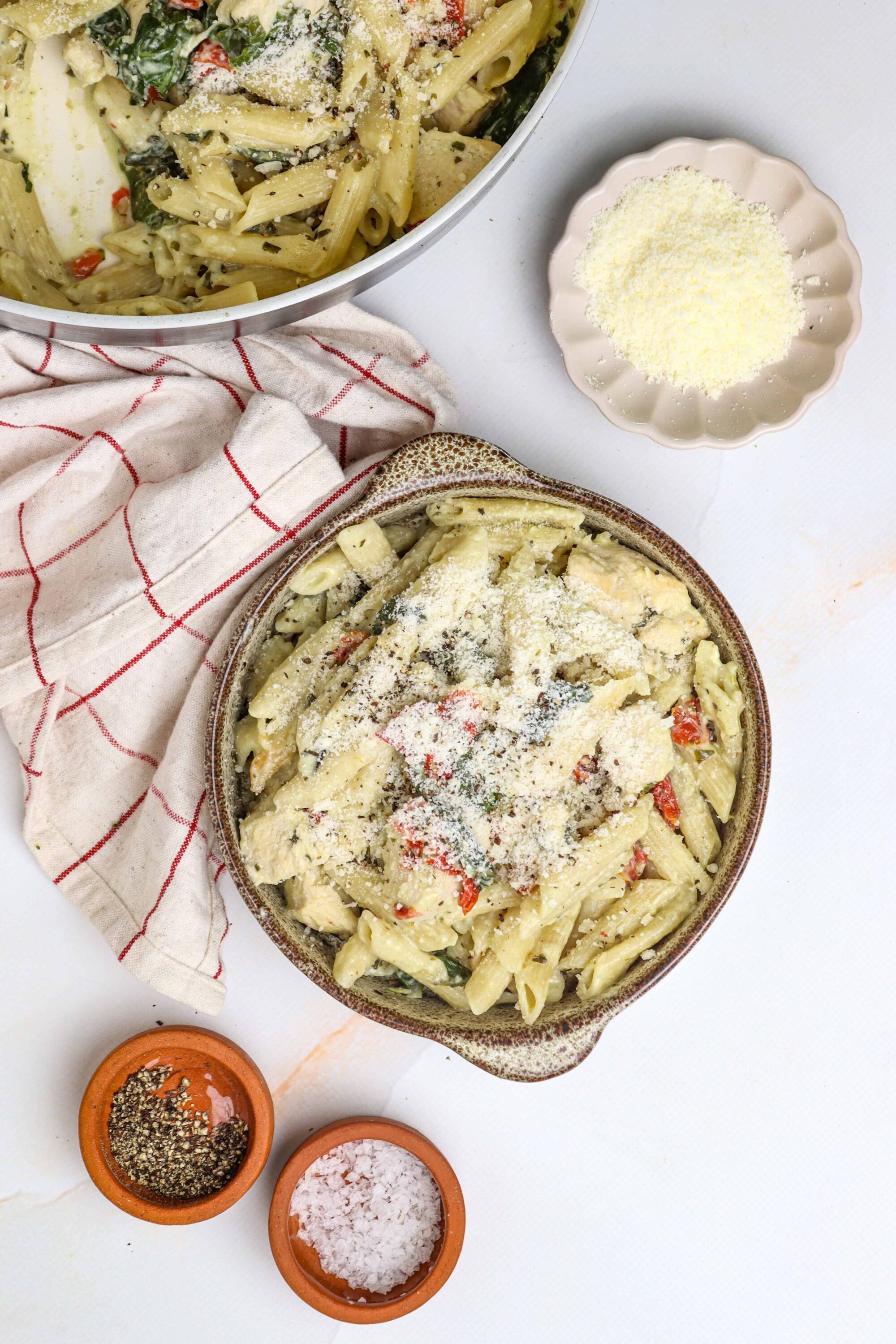 Creamy baked pasta with cheese, vegetables, and herbs on a rustic plate.