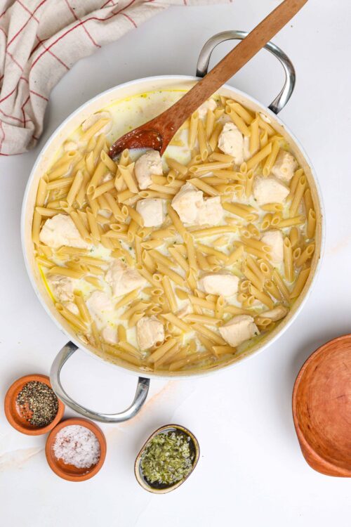 Creamy chicken pasta soup with penne and herbs, served in a white pot. Perfect comfort food recipe from Baked Bree.