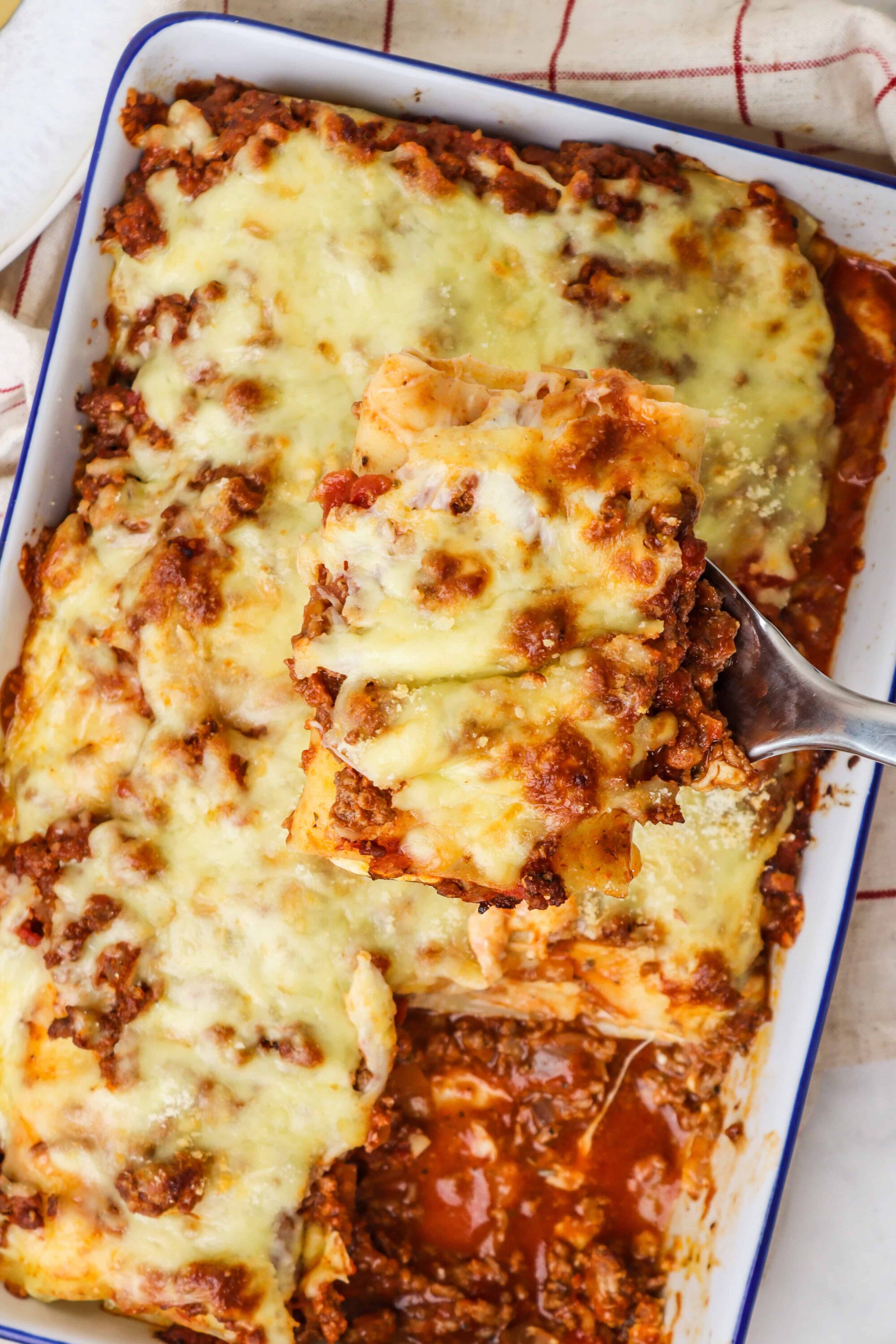 Creamy baked lasagna with melted cheese and savory meat sauce in a white casserole dish.