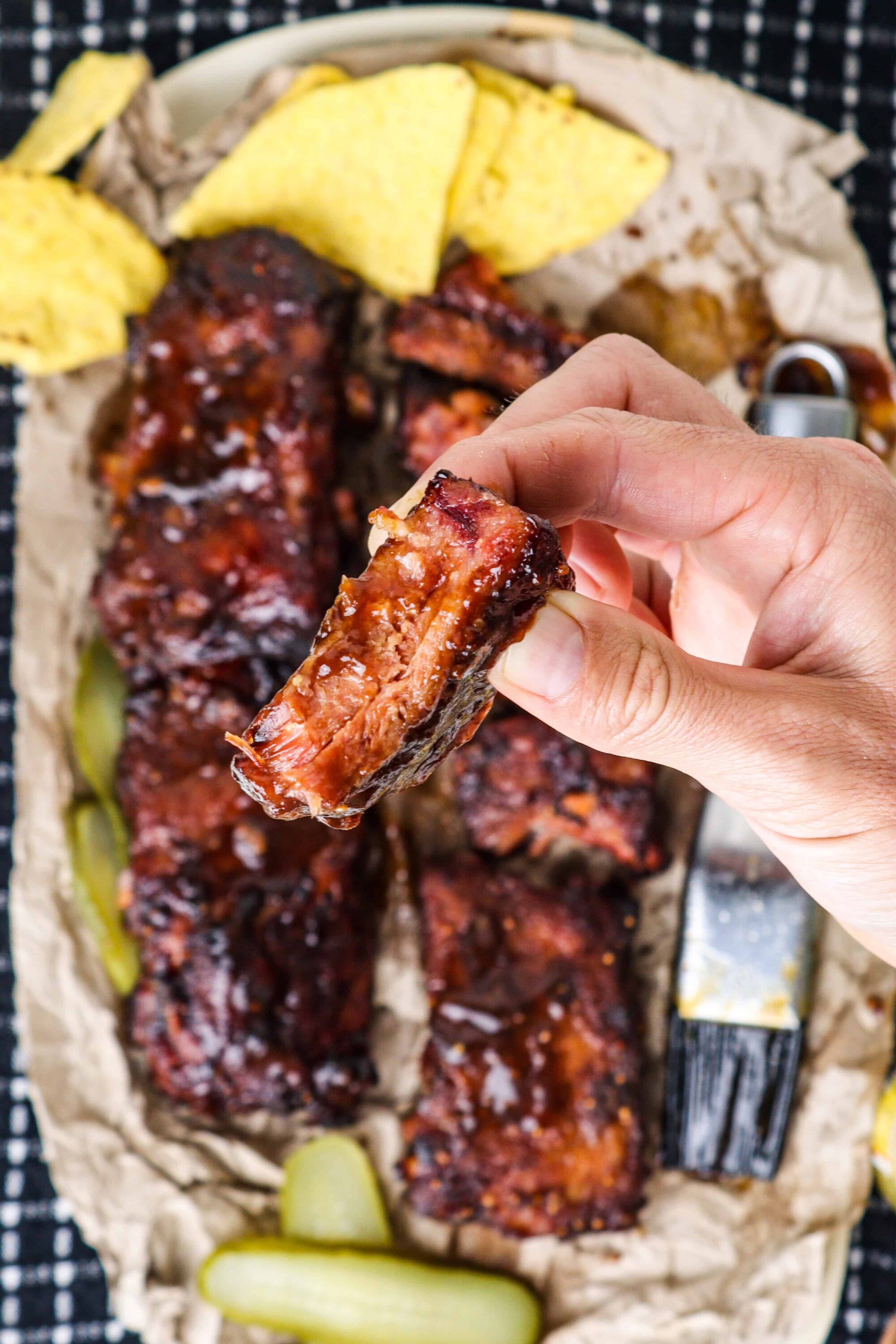 Succulent barbecue ribs with tangy sauce, served with pickles and potato chips.