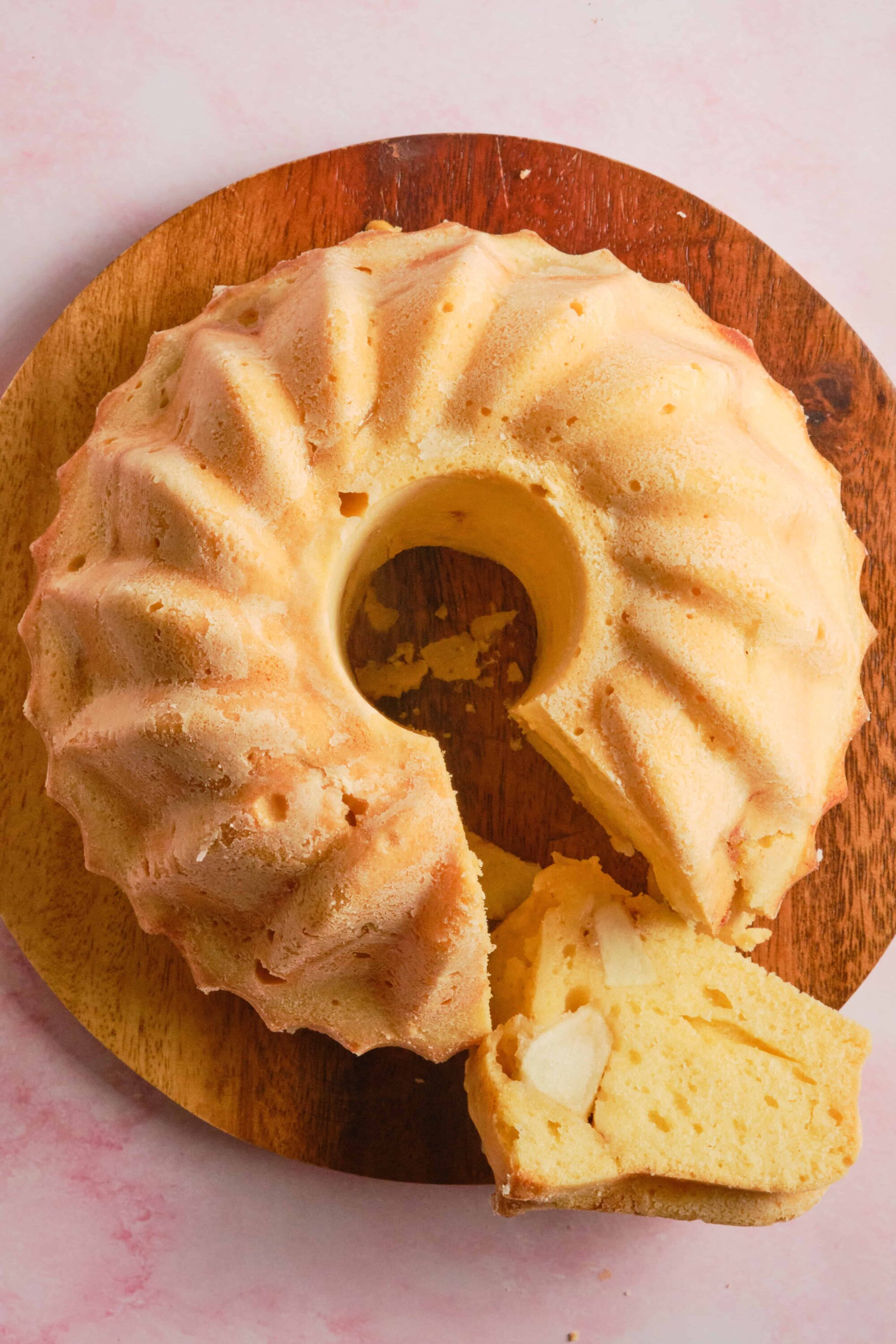 Fluffy lemon Bundt cake with slices of lemon, on a wooden board. Perfect for dessert or afternoon tea.