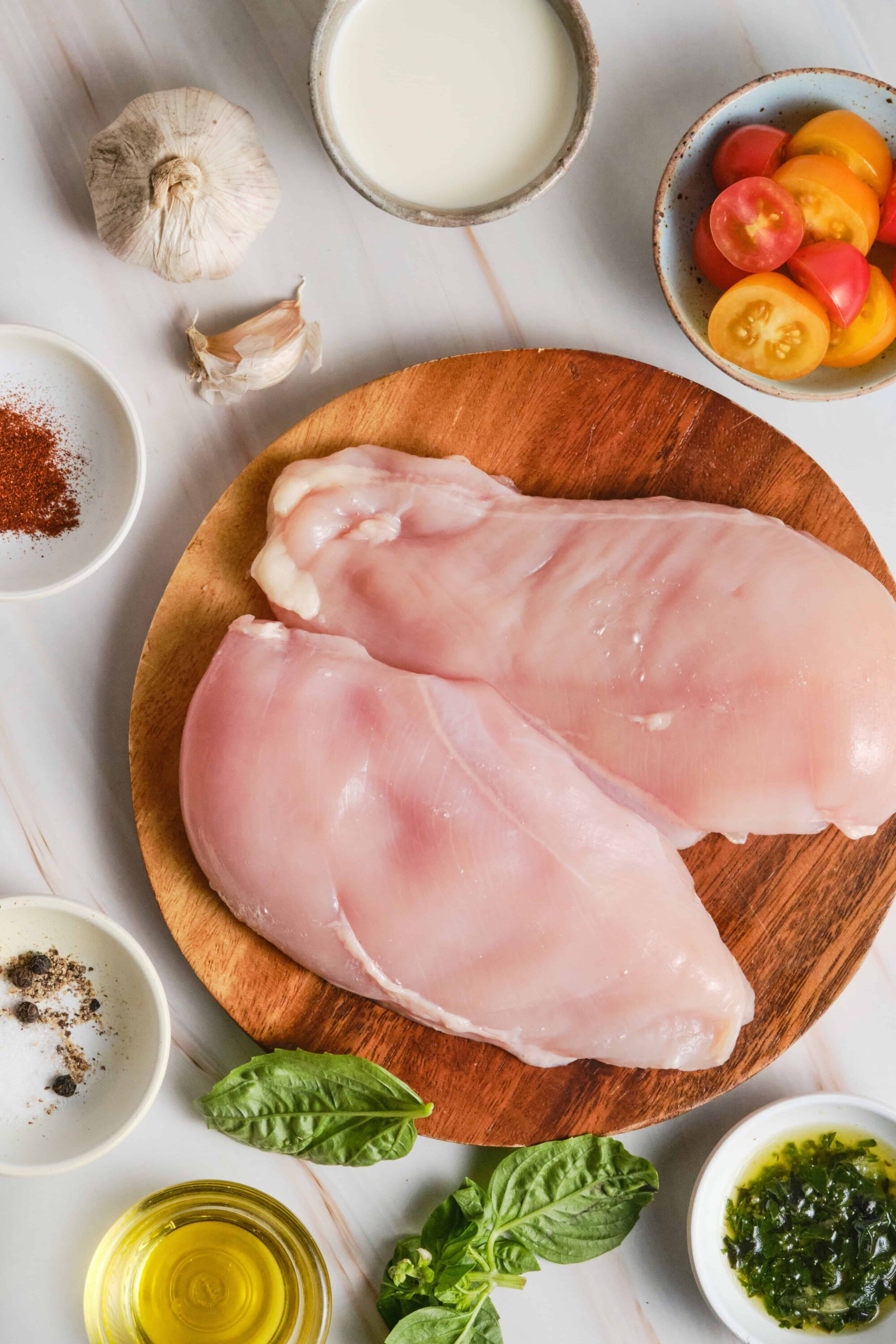 Juicy raw chicken breasts with garlic and fresh herbs on a wooden cutting board. Perfect for homemade recipes.