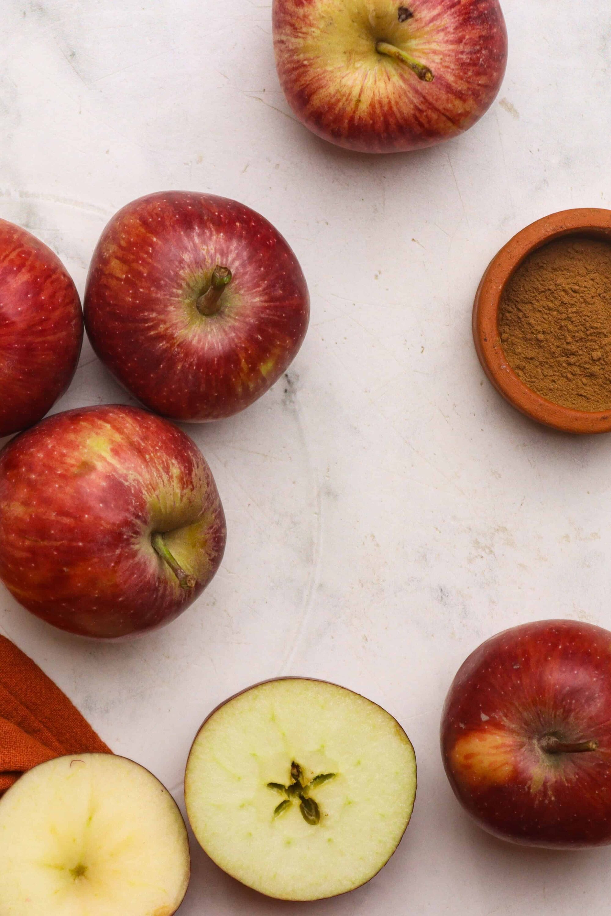 Fresh red apples with cinnamon powder on white background, apple pie ingredients for baking, healthy snack, baking, organic produce.