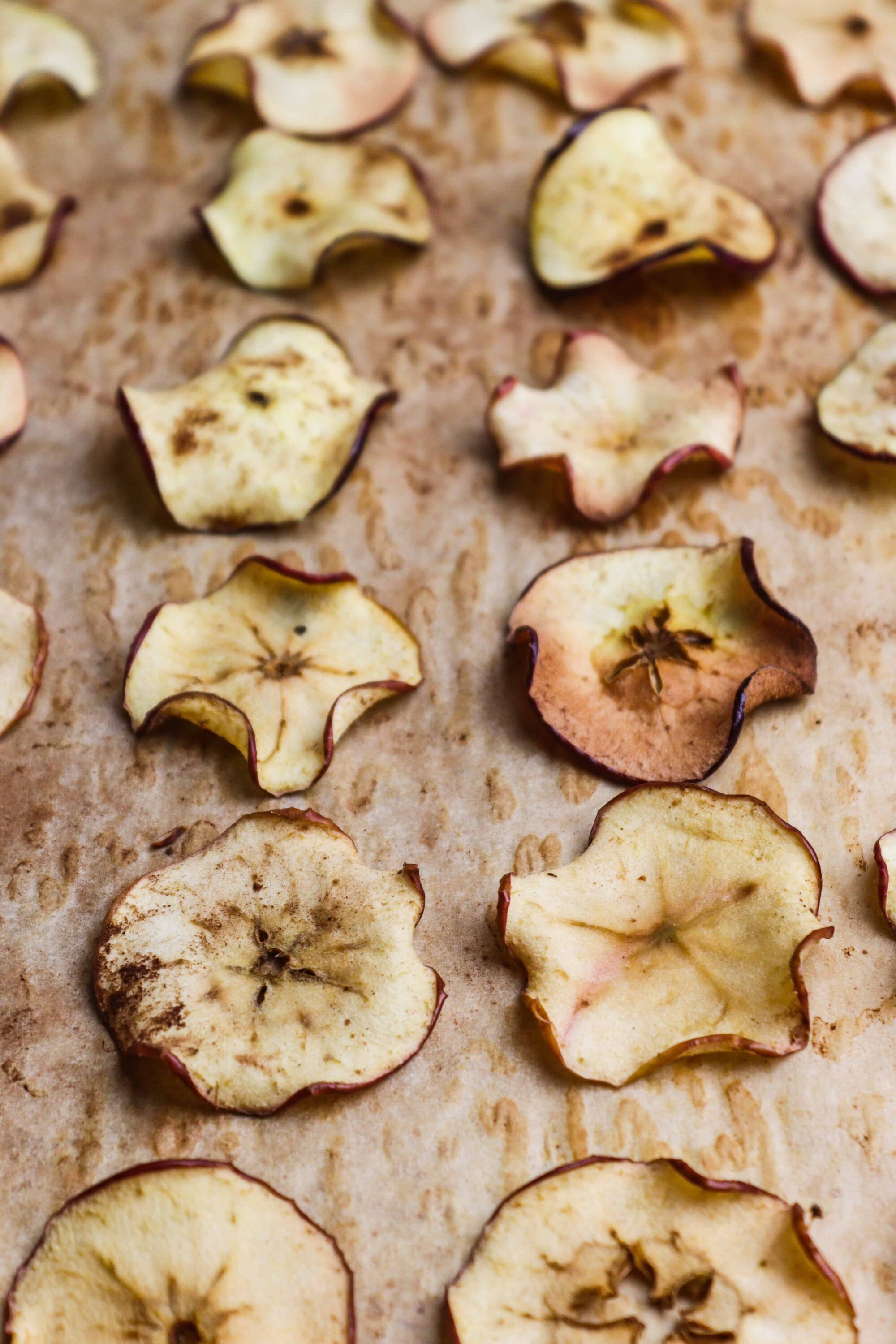 Dried apple slices on parchment paper, perfect for homemade fruit snacks or baking ingredients.