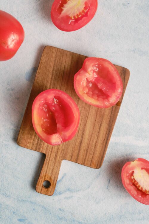 Juicy heirloom tomato halves on a wooden cutting board, fresh and vibrant for tomato recipes or salads.
