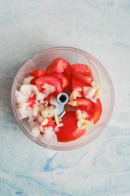 Fresh chopped tomatoes, onions, and garlic in a food chopper for homemade recipes.