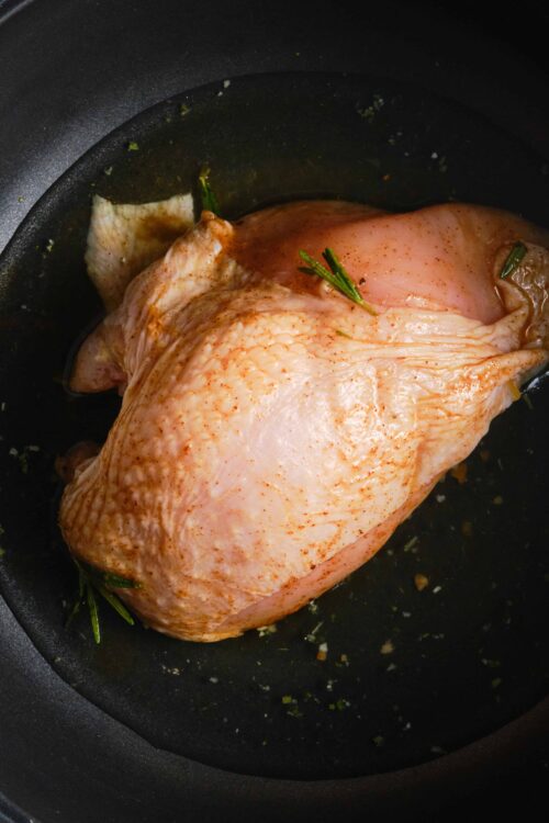 Succulent raw chicken breast seasoned with herbs in a skillet ready for cooking.