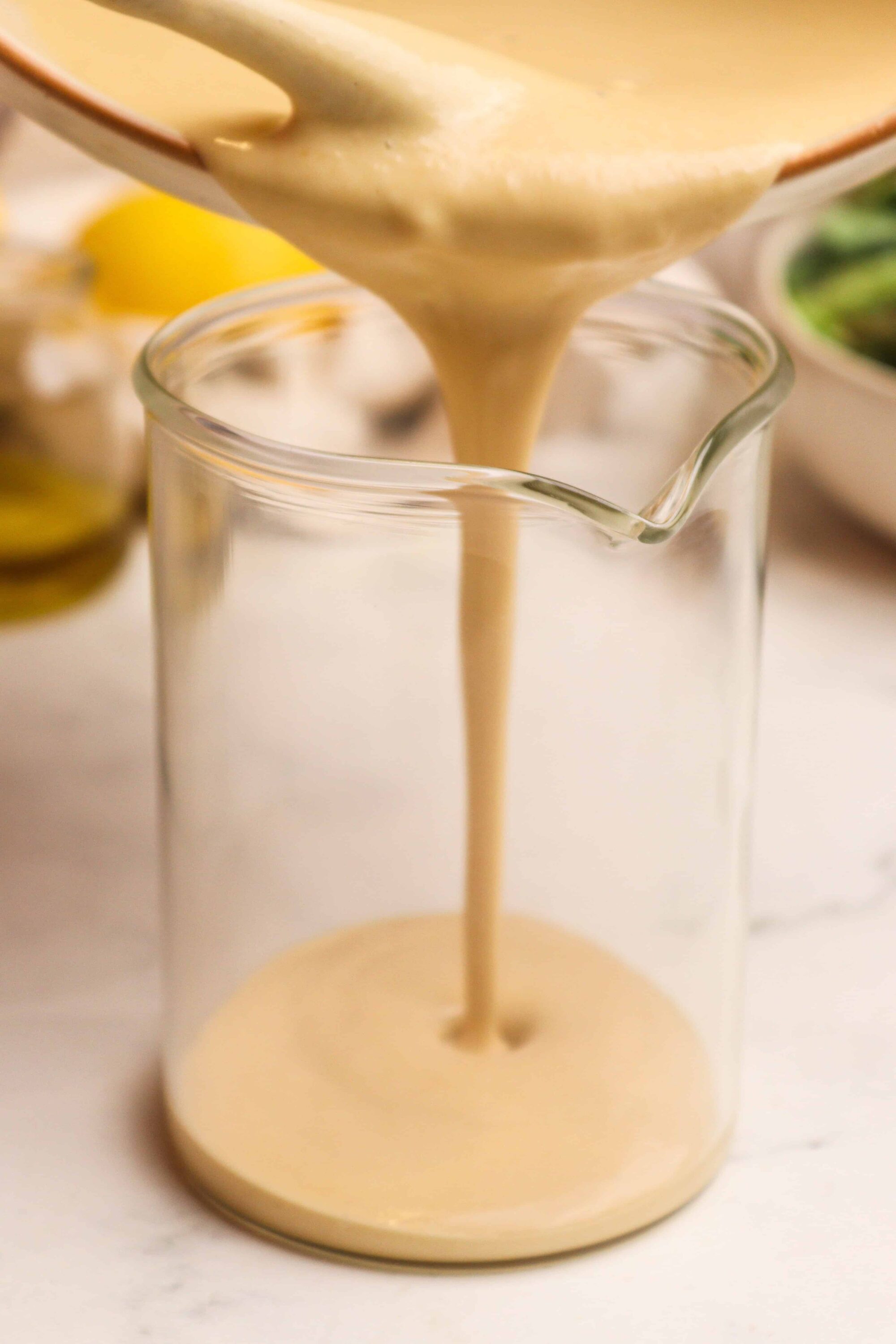 Creamy homemade béchamel sauce poured into a glass measuring cup for cooking or baking. Perfect for savory dishes and casseroles.