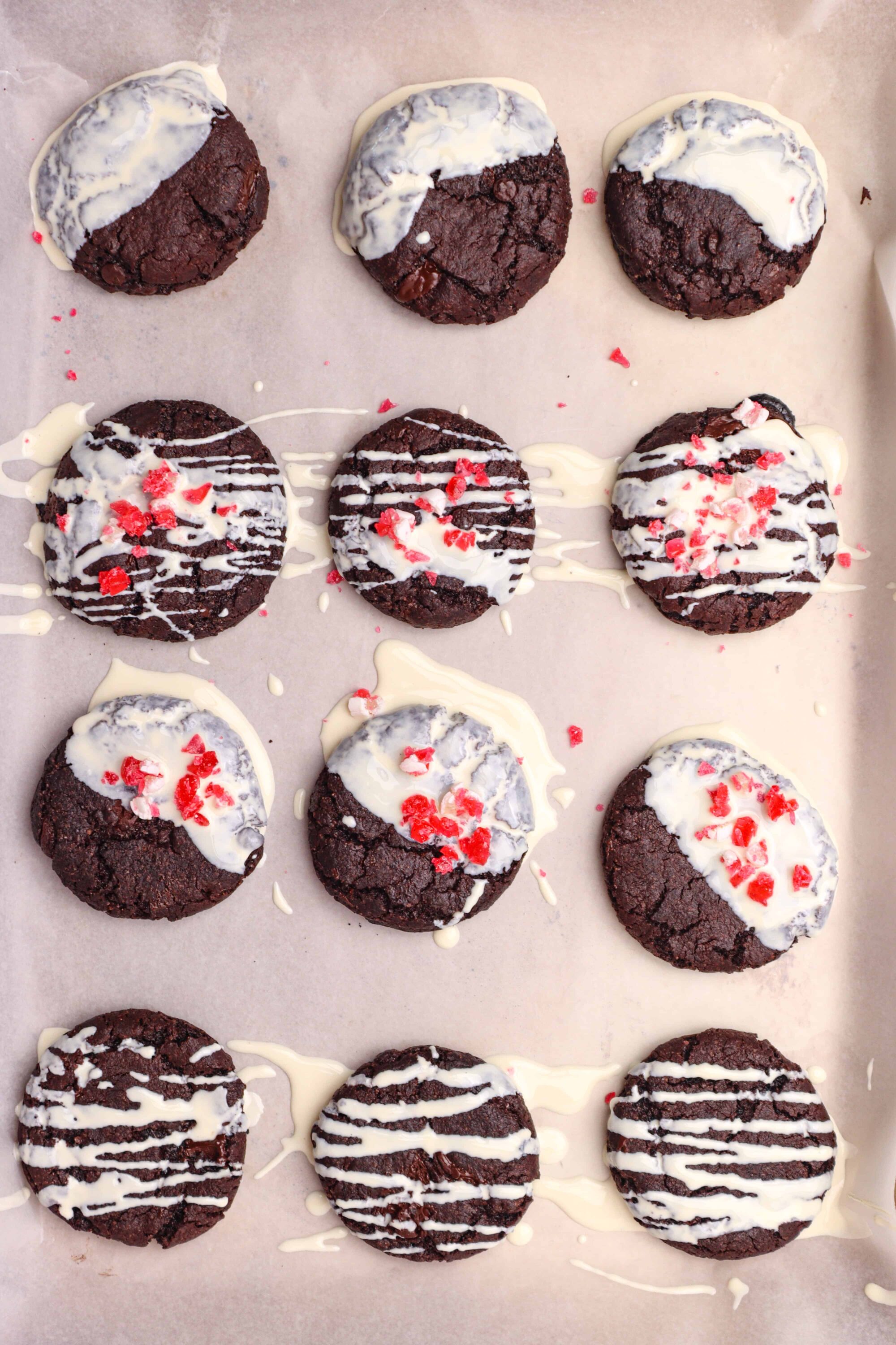 Rich chocolate cookies with white chocolate drizzle and red sprinkles, freshly baked and beautifully presented.