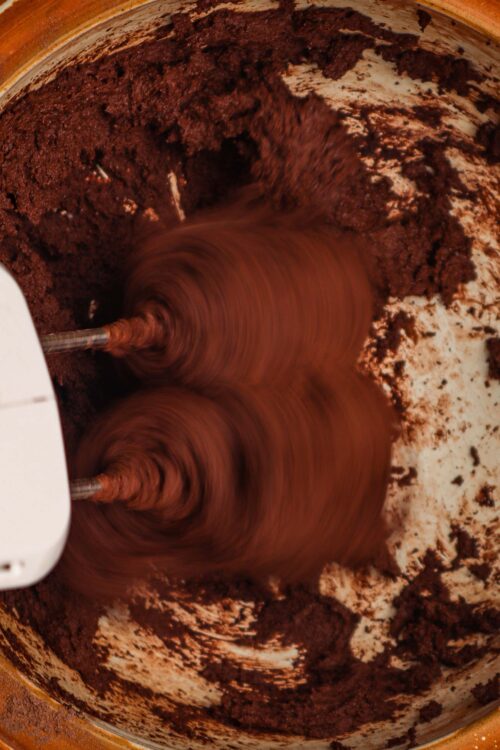 Smooth chocolate cake batter being mixed in a stand mixer.