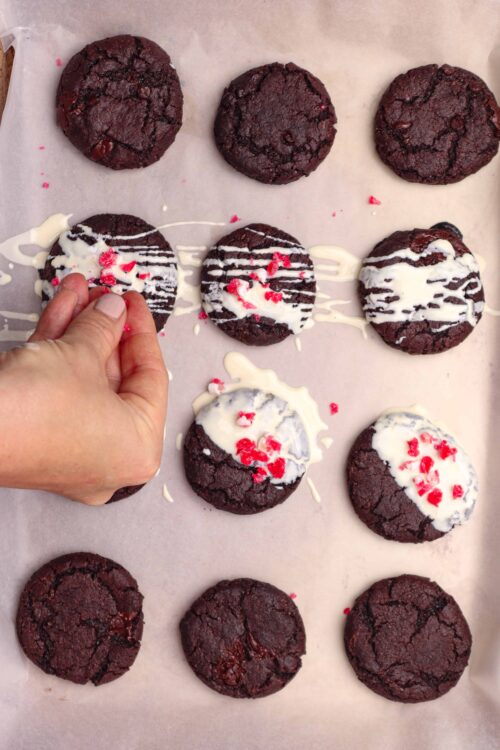 Rich chocolate cookies decorated with white chocolate drizzle and red sprinkles, baking process at Baked Bree.