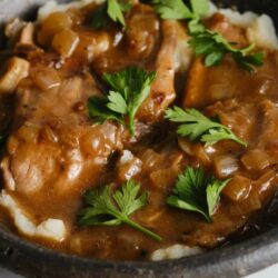 Savory beef stew with mushrooms and herbs in a rustic cast iron skillet.