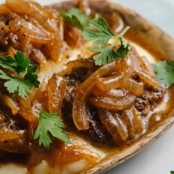 Savory meatloaf with caramelized onions garnished with fresh parsley on a rustic plate.