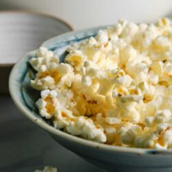 Buttered popcorn in a blue bowl, ready to serve at a movie night.