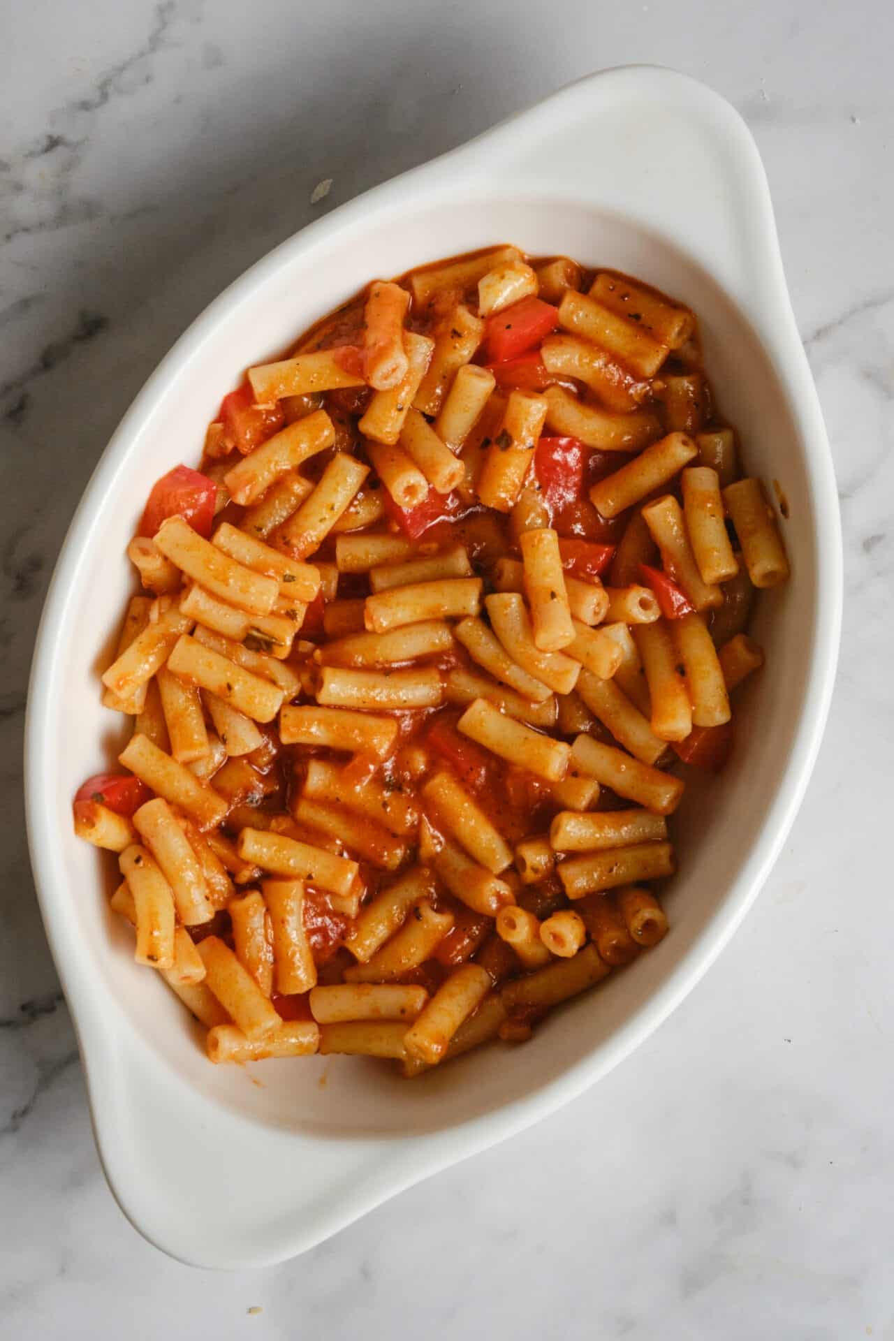 Creamy baked ziti pasta with marinara sauce and melted cheese in a white baking dish.