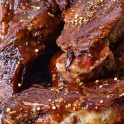 Succulent braised pork ribs glazed with barbecue sauce and sprinkled with crushed nuts, close-up.