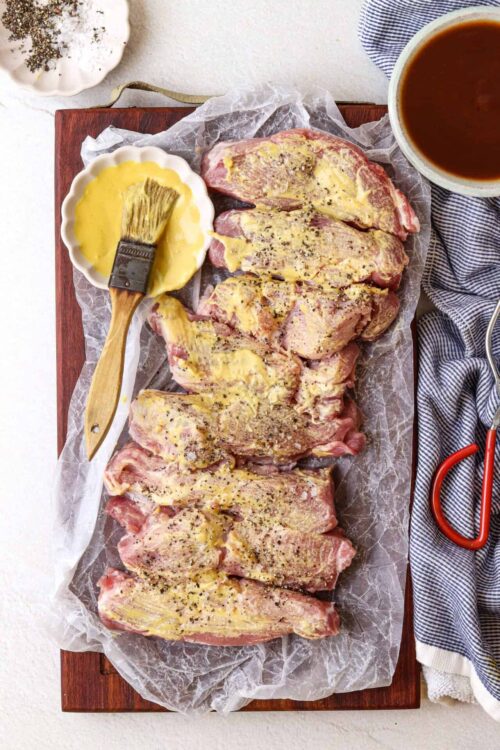 Succulent seasoned pork shoulder ready for roasting on parchment paper.