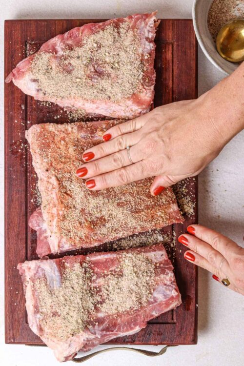 Seasoned pork ribs on a wooden cutting board ready for cooking.
