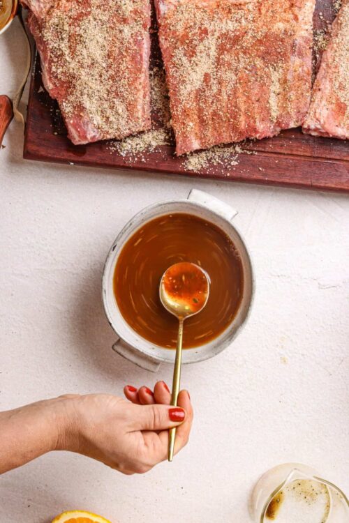 Juicy seasoned pork ribs with dry rub on a wooden cutting board over a light surface.