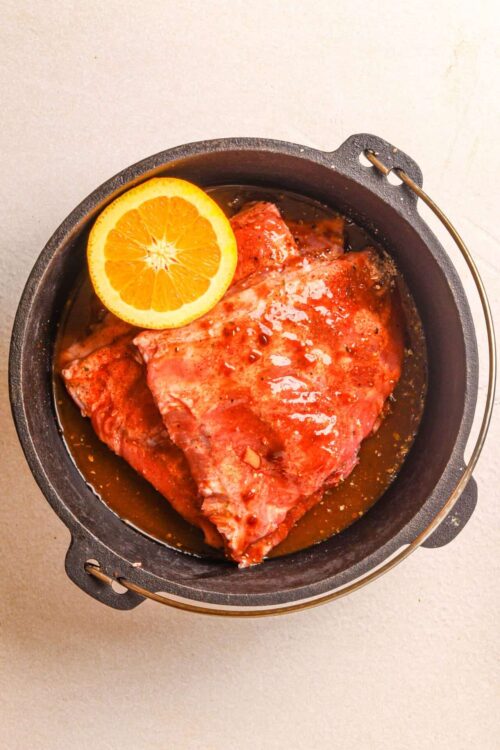 Juicy marinated steak with orange slices in cast iron skillet for flavorful baked recipes.