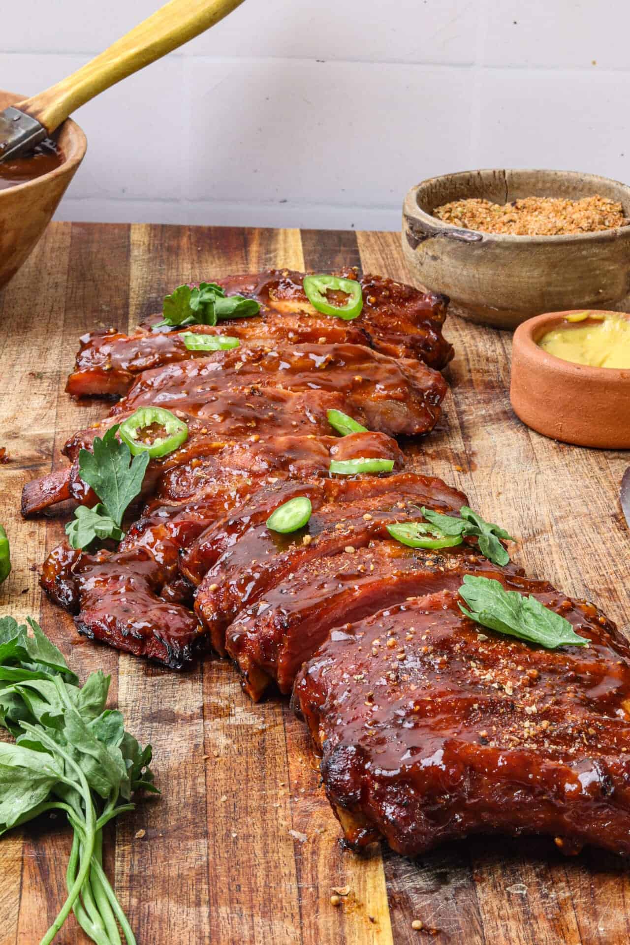 Juicy barbecue ribs glazed with sauce, garnished with fresh herbs on rustic wooden table.