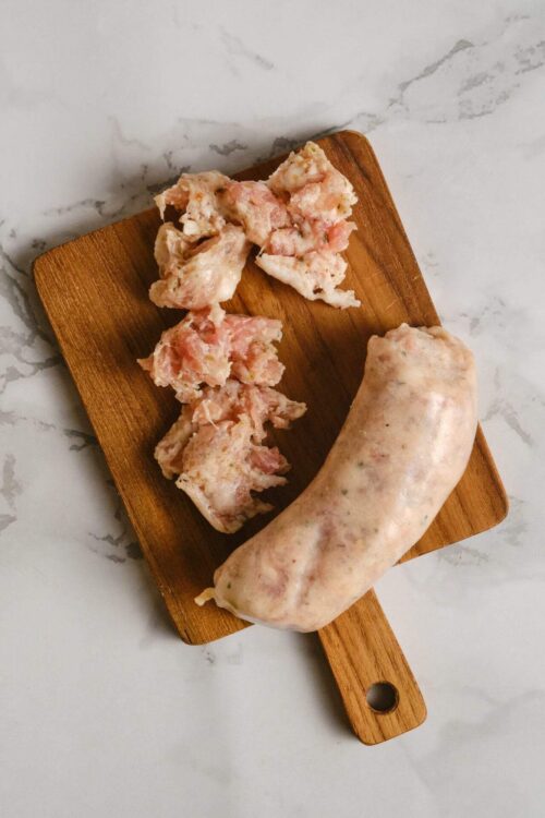 Fresh homemade sausage on a wooden cutting board, ready for cooking or grilling.