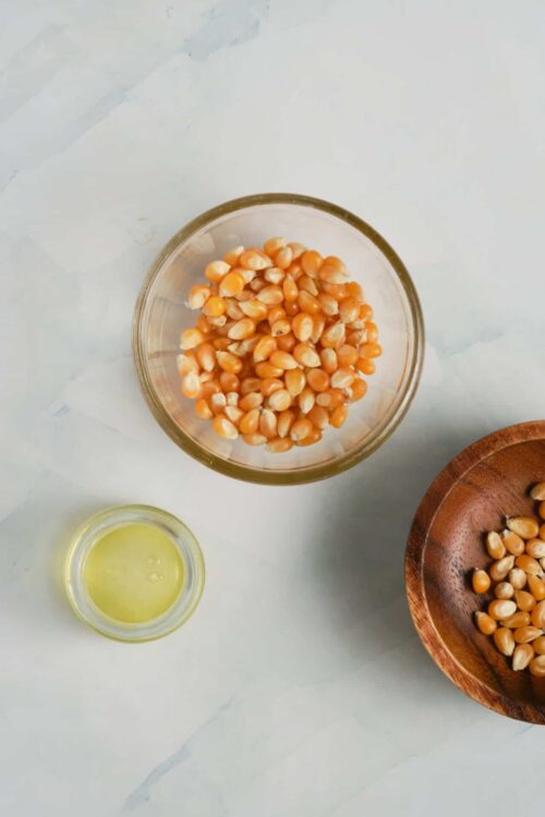 Softened popcorn kernels in glass bowl with oil, ready for popcorn making.