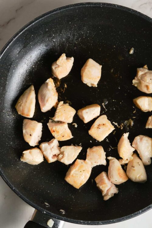 Sautéed chicken breasts in a black skillet for healthy cooking recipes.