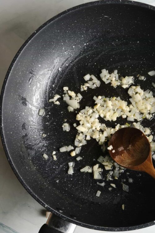 Sautéing chopped onions in a non-stick skillet for cooking or flavoring recipes.