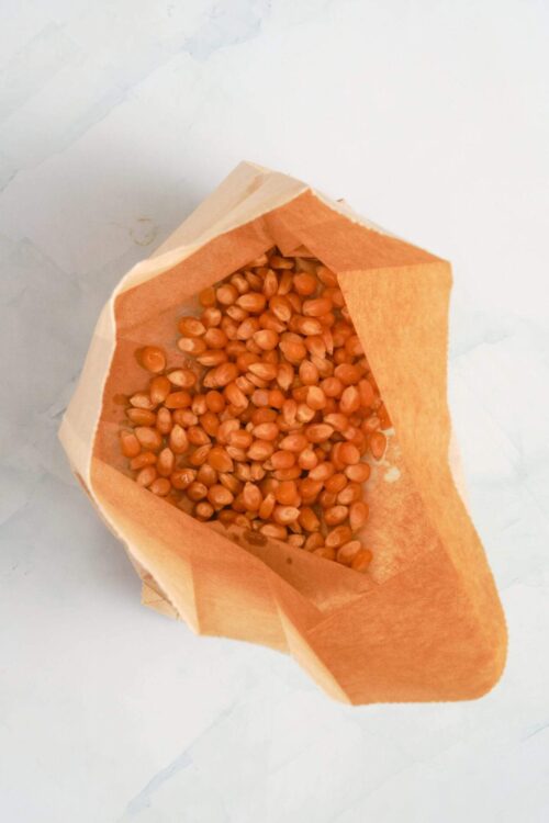 Raw popcorn kernels in paper bag for homemade popcorn.