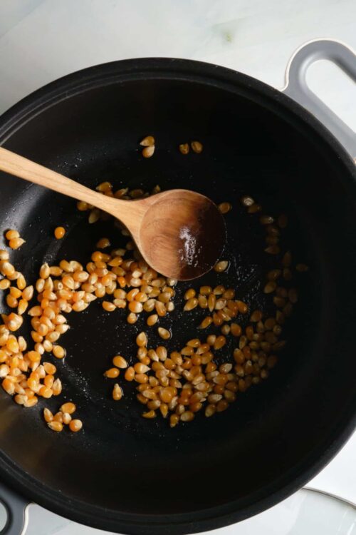 Golden toasted lentils in a black skillet with a wooden spoon.
