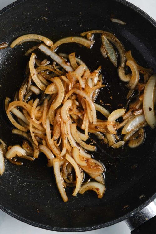 Sautéed onions in a frying pan with caramelized edges.